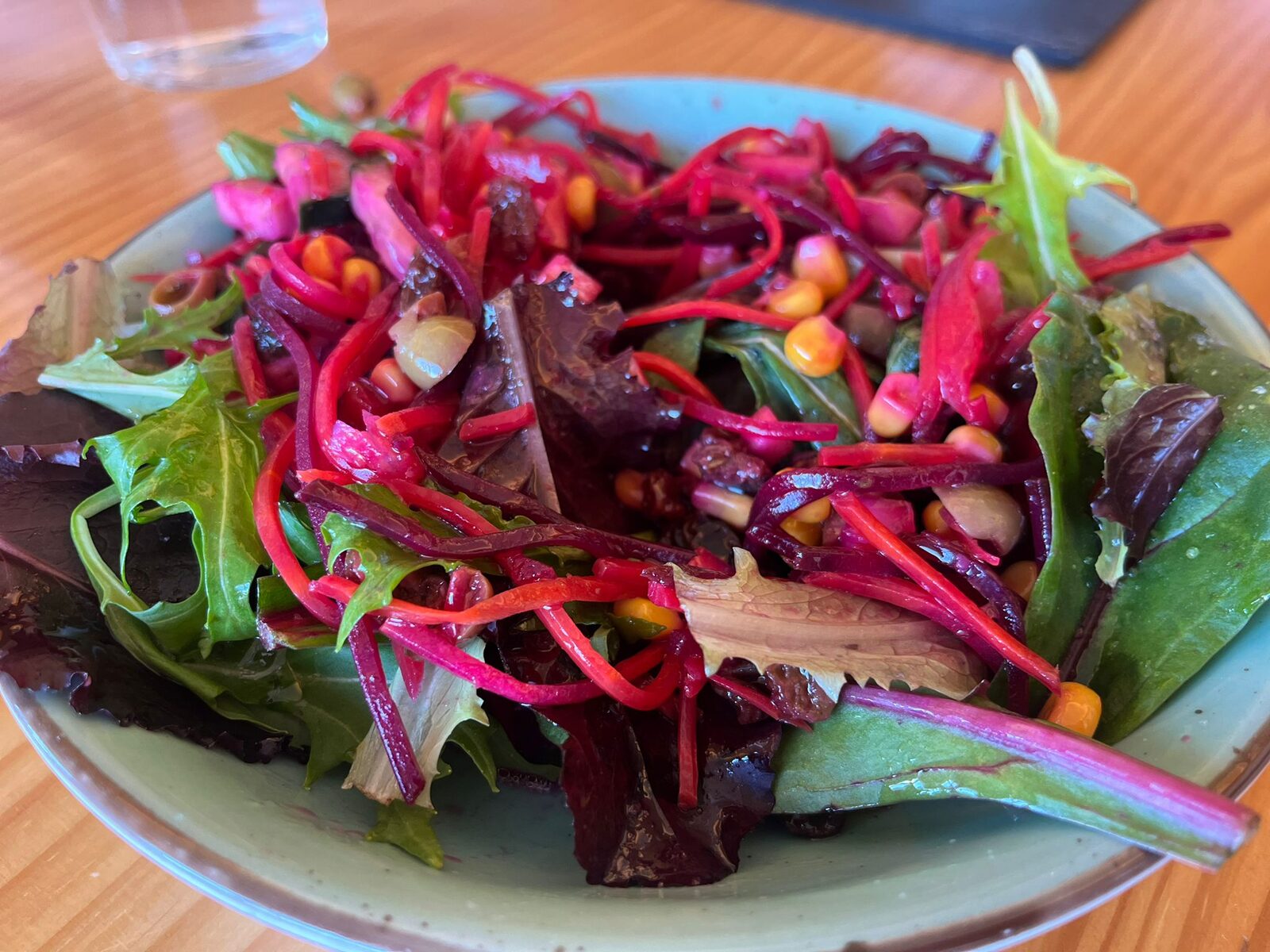 Un cuenco de ensalada de brotes, remolacha y granada de la cocina de Mar de Fulles, sobre la mesa de madera del comedor