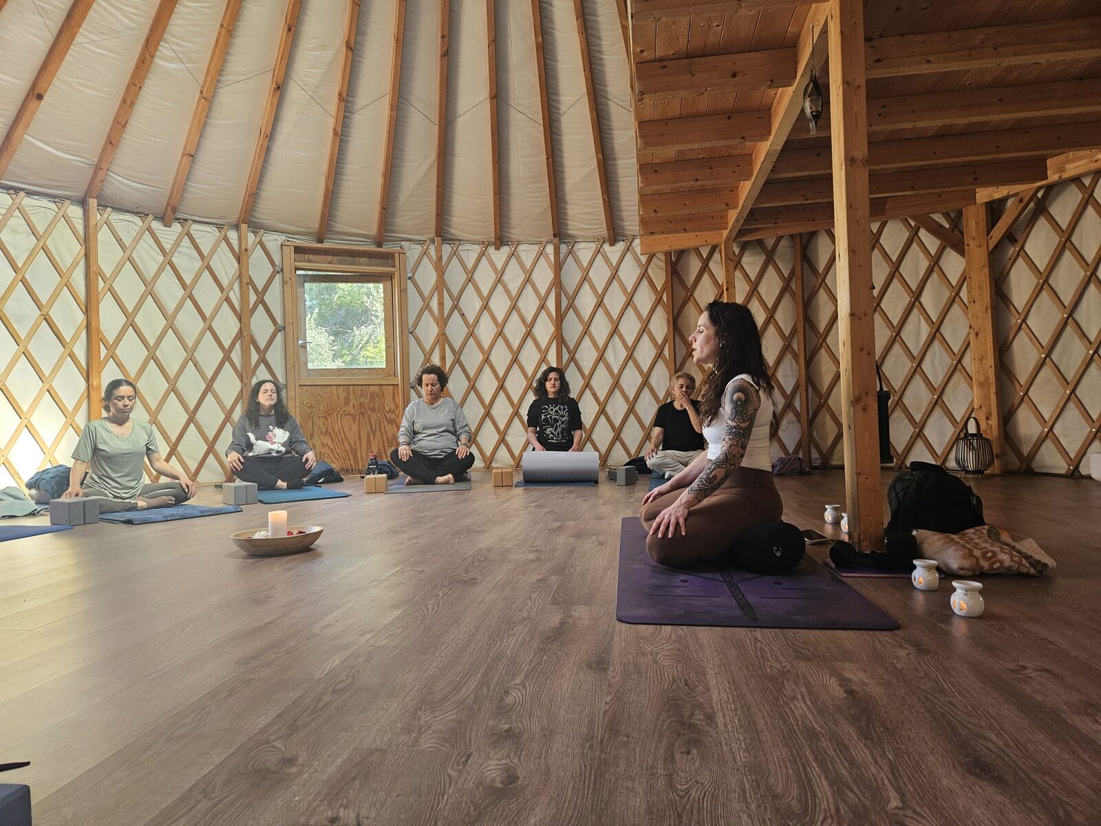 El grupo sentado en círculo sobre las esterillas en la yurta, con Sara guiando la práctica de yoga