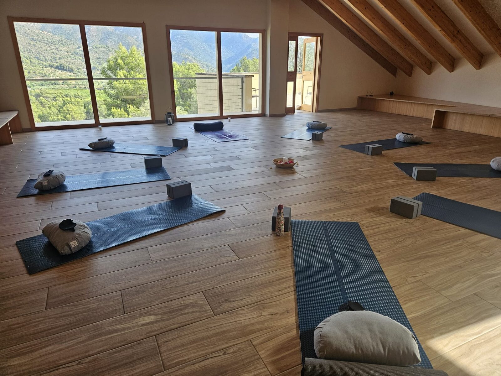 La sala de Mar de Fulles preparada antes del taller: esterillas, bloques y cojines repartidos por el suelo y los ventanales abiertos al valle