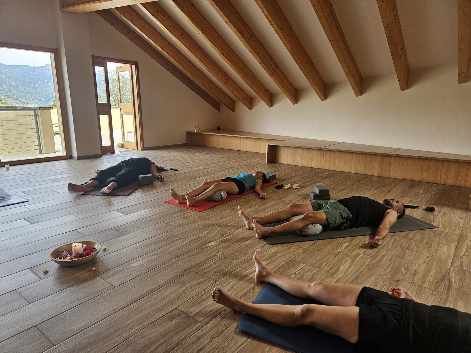 El grupo del taller en savasana, tumbado sobre las esterillas de la sala con la luz del valle entrando por los ventanales